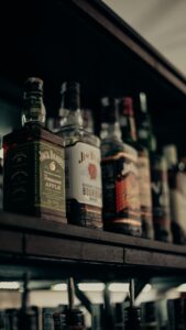 Aesthetic close-up shot of various whiskey bottles arranged neatly on a bar shelf.